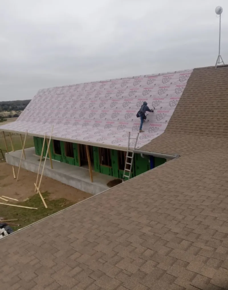 Worker preparing underlayment for a metal roof installation in Fort Stockton